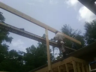 Carpenter setting a ridge beam over a new addition frame — Ice Dam Removal by Roofing Brothers in Colt