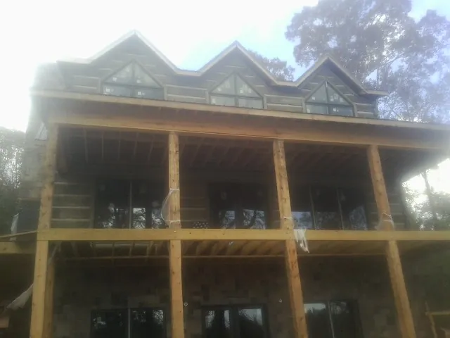 Dormers and porch framing on a large log home under construction — Roof Coating work by our crew in Colt