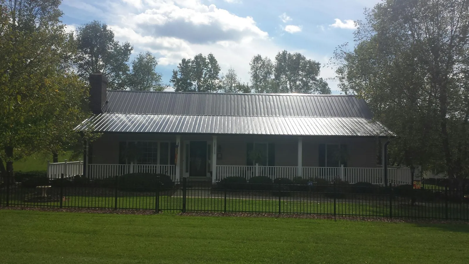 Gray metal roof on a brick ranch with a full width front porch — Gutter Guard Installation work by our crew in Colt
