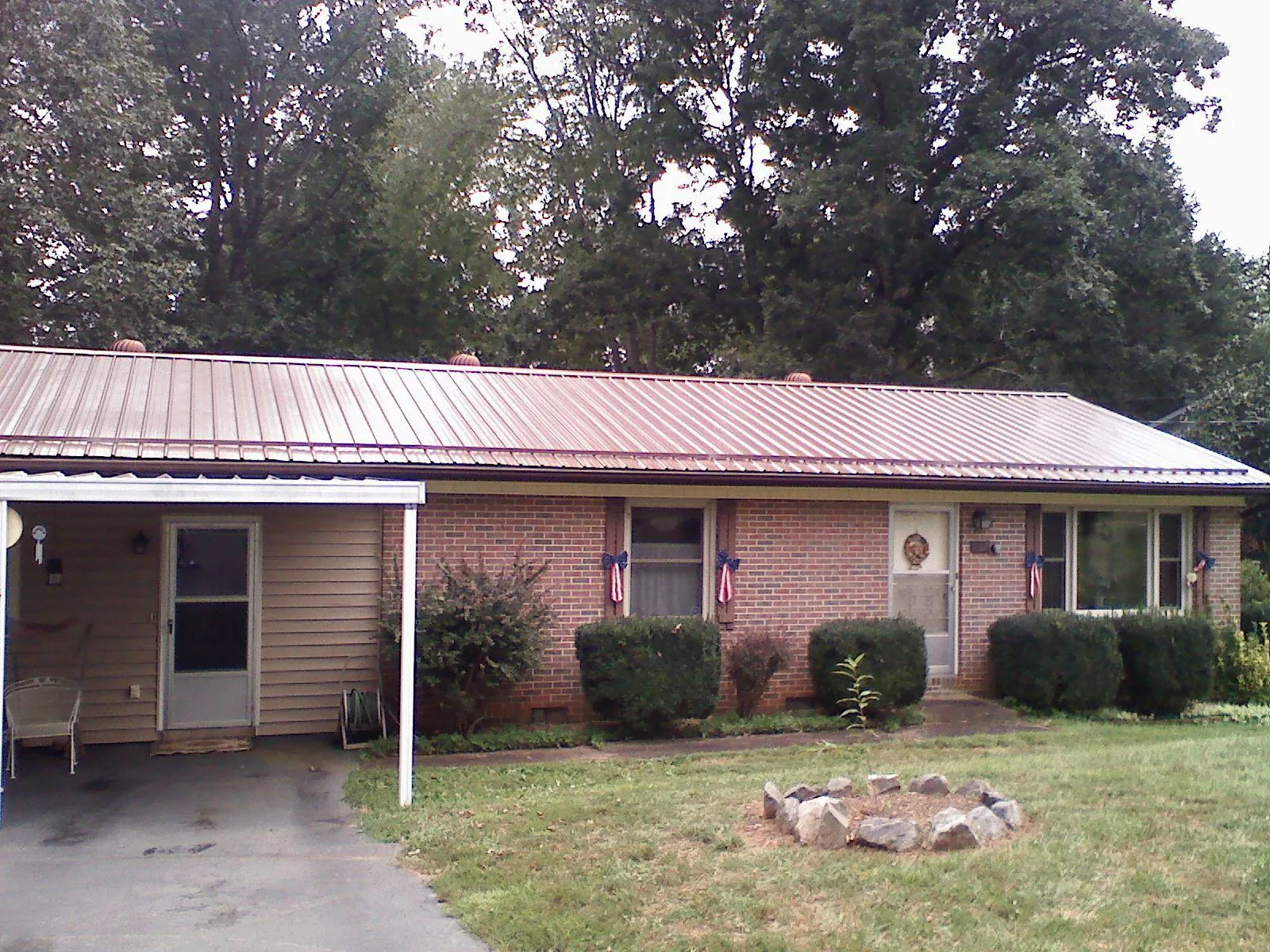 Bronze metal roof and carport on a brick ranch home — Roof Repair work by our crew in Colt